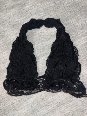 Svart spetsbralette med halterneck - Säljer en svart bralette i spets med halterneck-modell. Bh:n har djup urringning och bred spetskant nedtill. Ingen vaddering eller bygel, vilket ger en mjuk och bekväm känsla.
