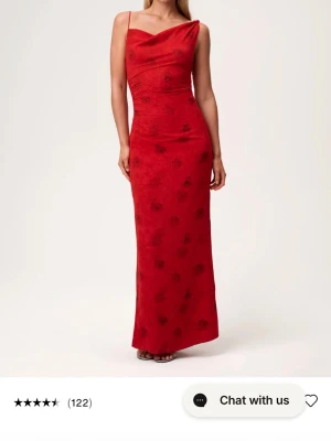 Röd långklänning med blommönster adoore - Elegant röd långklänning med tunna axelband och subtilt blommönster. Klänningen har en draperad urringning och figurnära passform som framhäver siluetten. Perfekt för speciella tillfällen där du vill sticka ut. Pris kan diskuteras vid snabb affär. Endast testad, söker då jag köpte fel storlek.