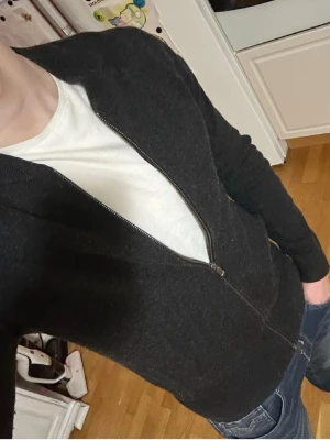 Svart ziptröja från Massimo dutti - Snygg svart ziptröja från Massimo dutti med stilren design och rund hals. Tröjan har dragkedja framtill och är tillverkad i mjukt material som känns skönt mot huden. Perfekt att slänga på över en t-shirt för en avslappnad look.