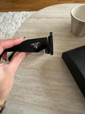 Svarta solglasögon från Prada - Svarta solglasögon från Prada! Väldigt fint skick, endast använda ca 2 gånger. Inhandlades på landvetter flygplats. Finns inget kvitto men finns kartong, dustbag och fodral för glasögonen. Säljer endast då de inte passar mitt ansikte! Annonsen ligger ute på flera sidor! Pris kan diskuteras ❤️