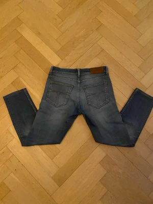 Blå slim fit jeans med slitningar - Tiger of Sweden Slim Fit Jeans – W28 L32 i modellen EVOLVE, tillverkade i Italien. Storlek W28 L32, men längden motsvarar mer L30. Snygg passform med klassisk tvätt med femficksdesign – perfekta både till vardags och lite mer uppklätt Kontakta vid frågor! 