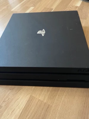 PlayStation 4 Pro spelkonsol svart - Säljer en svart PlayStation 4 Pro från Sony. Konsolen har en stilren, fyrkantig design med PlayStation-loggan i silver på ovansidan. Tillverkad i plast och passar perfekt för gaming och underhållning hemma. OBS ingen kontroll 