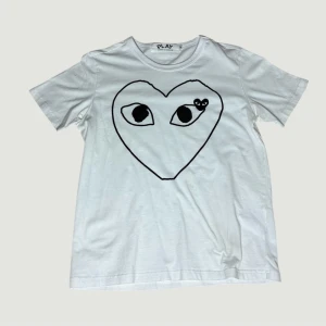 CDG T-SHIRT  - Säljer en unik T-shirt från Comme des Garçons Play med ett stort svart hjärta och ögon tryckt på framsidan. Klassisk rund hals och korta ärmar. Materialet är mjuk bomull som känns skönt mot huden. Har några fläckar som borde gå bort vid tvätt men är inte helt hundra, förklarar därför de billiga priset. Hör av er vid minsta fundering, priset är diskuterbart vid snabb och smidig affär!