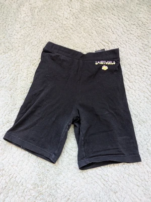 Svarta cykelshorts från H&m SmileyWorld - Svarta cykelshorts från H&m SmileyWorld med broderad logga och en liten gul smileyblomma framtill. Mjukt och stretchigt material som passar perfekt till sommaren. Enkel och clean design med elastisk midja.