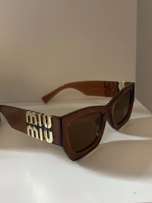 Bruna solglasögon från Miu Miu - Säljer dessa bruna solglasögonen från Miu Miu . Dom är köpta här på Plick och säljer för att dom inte passade mig. Dom är lyxiga med en guld logga och passar perfekt till sommaren!