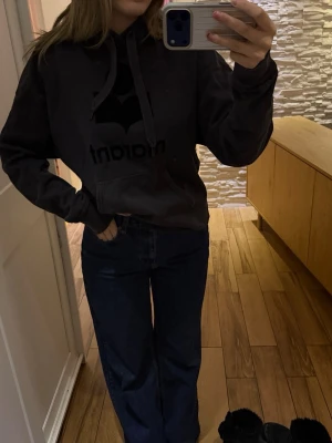 Isabel marant hoodie - Säljer en svart hoodie från isabel marant  med stort svart tryck på bröstet och klassisk känguruficka. Hoodien har huva med dragsko och är gjord i mjukt bomullsmaterial. Perfekt för en chill och avslappnad stil.