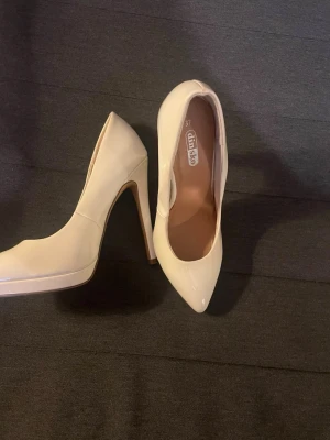 Beige lackpumps från Din Sko - Snygga beige pumps från Din Sko i storlek 37. Skorna har en klassisk spetsig tå, hög klack och är tillverkade i glansigt lackmaterial. Perfekta för att lyfta vilken outfit som helst med sin stilrena look.