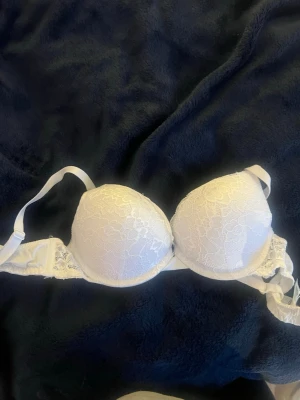 Vit spets-bh från Linnea 70A - Säljer en vit bh från Linnea med vadderade kupor och vacker spetsdetalj över hela framsidan. 