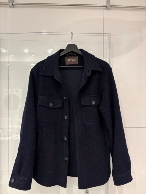 Mörkblå overshirt från Oscar Jacobson - Säljer nu en fet overshirt från Oscar Jacobsson. Materialet är ullblandning och är knappt använd. Nypris ligger runt 3000