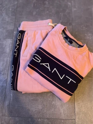 GANT-set - GANT set – storlek 158/164 (13–14 år) Sparsamt använt och i fint skick! Mjukisbyxor + sweatshirt i rosa med marinblå detaljer och logo. Superfint och bekvämt set som passar perfekt till vardag eller mys.