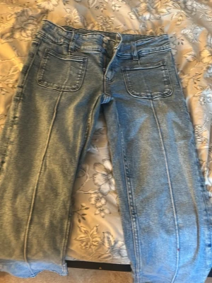 Ljusblå jeans med raka ben - Säljer ett par ljusblå jeans med raka ben och stora framfickor. Jeansen har hög midja och klassisk femficksdesign med tydliga sömmar framtill. Perfekta för en avslappnad och trendig stil.