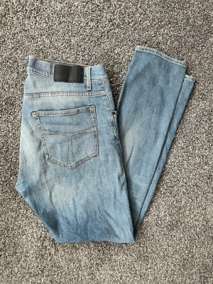 Ljusblå tiger of sweden slim fit jeans - Snygga ljusblå jeans med slim fit passform och klassisk femficksdesign. Jeansen har en lätt tvättad look med slitningar framtill och raka ben. Perfekta för en avslappnad och trendig stil.