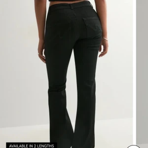 Svarta bootcut jeans från Nelly - Säljer ett par svarta bootcut jeans från Nellu med låg midja och klassiska fickor i bak. Jeansen har en snygg utsvängd passform och stängs med knapp och dragkedja. Använda endast en gång då de inte passade mig riktigt. Original pris 699kr.
