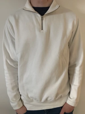 Vit halvzip sweatshirt från Zara - Vit sweatshirt med halv dragkedja från Zara. Tröjan har hög krage, långa ärmar och ribbade muddar vid ärmslut och nederkant. Tillverkad i mjukt material som känns skönt mot huden. Perfekt för en avslappnad och stilren look.