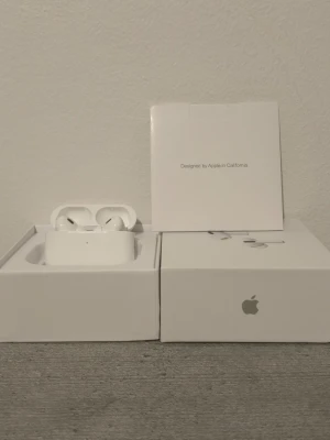 Apple AirPods Pro gen 2 - Säljer ett par vita Apple AirPods Pro med trådlöst laddningsetui. Snygg och kompakt design i blank plast, perfekt för dig som vill ha grymt ljud och smidig anslutning till din iPhone eller andra Apple-enheter. Levereras i originalförpackning.
