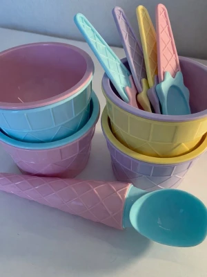 Glasskålar och skedar i pastellfärger - Säljer ett set med glassskålar och matchande skedar i pastellfärger som rosa, blå, gul och lila. Skålarna och skedarna har ett mönster som påminner om glassvåfflor och är tillverkade i plast. Perfekt för glass eller dessert. Oanvänt