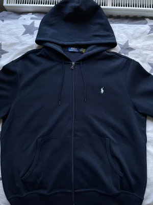 Ralph Lauren - Säljer en Polo Ralph Lauren kofta i storlek XXL med vit logga som jag fick som födelsedagspresent för ett tag sedan. Koftan är för stor och har bara legat i mitt rum utan någon användning. Har bara provat koftan!