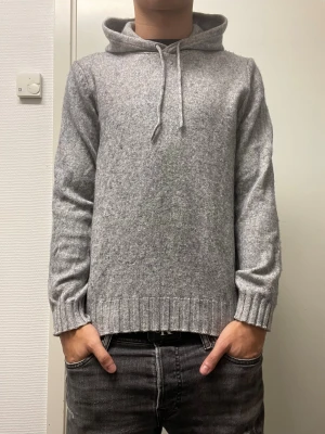 Stickad hoodie från Dressman - Fet grå stickad hoodie. Storlek M men har krympt så passar S bättre. Har några små vita fläckar vid vänstra handleden och även en liten fläck på magen som knappt syns, annars bra skick. Modellen är 173cm, 64kg. Pris kan diskuteras!