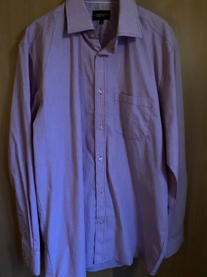 Ljuslila skjorta från Gent - Snygg ljuslila skjorta från Gent med klassisk krage och bröstficka. Skjortan har knappar hela vägen och långa ärmar med manschett. Perfekt för dig som gillar stilrena plagg med en twist på färgen.