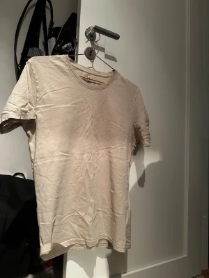 Beige t-shirt från SOC i bomull - Snygg beige t-shirt från SOC i storlek M. Klassisk rund hals och korta ärmar, tillverkad i mjuk bomull. Perfekt basic-plagg med enkel design som funkar till allt. Neutral färg som är lätt att matcha med andra kläder.