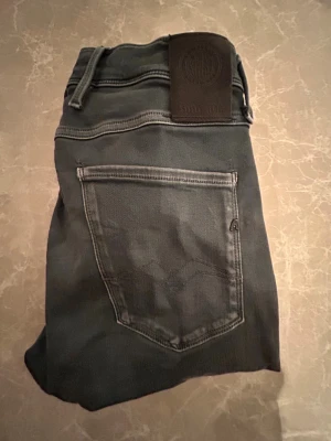 Replay blå/grå  jeans Anbass tapered - Svarta jeans från Replay, modell Anbass med tapered passform. Klassisk femficksdesign, svarta sömmar och Replay-logga på bakfickan. Jeansen har en snygg, smal siluett och är tillverkade i stretchigt denim för extra komfort.