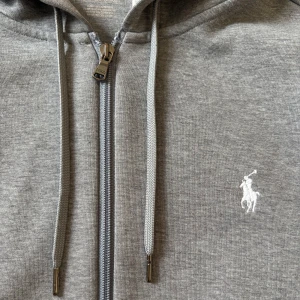 Grå Polo Ralph Lauren Zip Hoodie  - Säljer denna gråa zip Hoodien från Ralph lauren i storlek S. Den är i bra skick och inte använd så mycket. Perfekt till sommaren som snart är här . Om ni är intresserade hör gärna av er. Har en mörkblå med på min sida så om man är intresserad av båda ska vi kunna lösa ett bättre erbjudande.