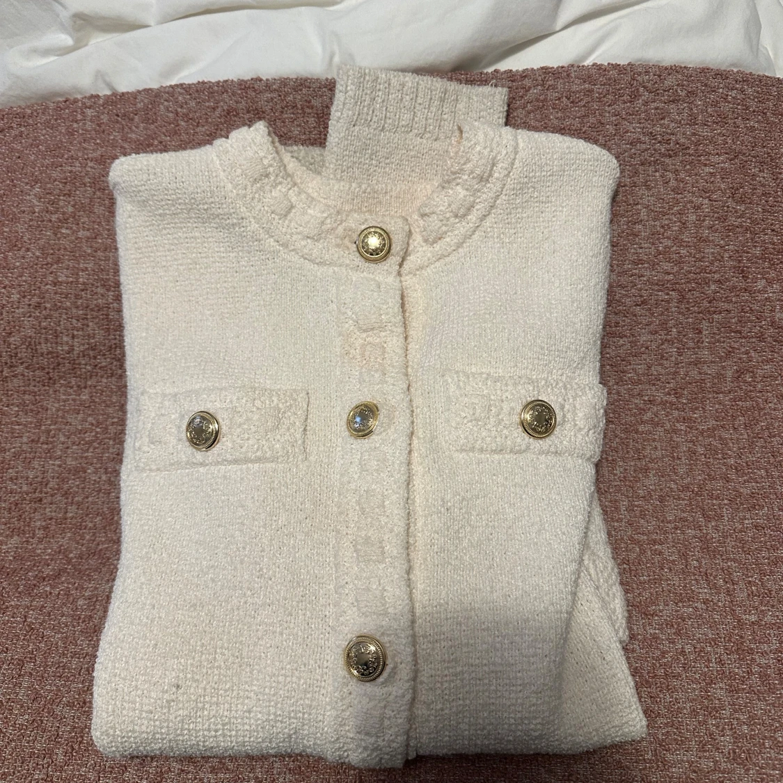 Vit kofta med guldknappar