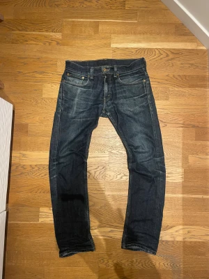 Levi's 511 mörkblå jeans W32 L30 - Säljer ett par Levi's 511 jeans i mörkblå tvätt med klassiska fem fickor och snygga slitningar. Modellen är slim och har raka ben med låg midja. Jeansen är tillverkade i slitstarkt bomullsmaterial och har den ikoniska Levi's-lappen bak. Alla mått finns och de är enbart att fråga om 