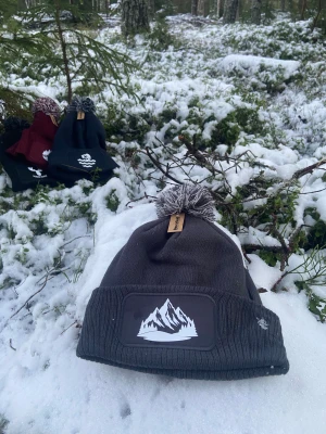 Mössa med Berg  - En mörkgrå mössa med vit tryck på, trycket är ett berg. Helt oanvänd då vi själv har tryckt den. Mössan samt trycket är av bra kvalitet.