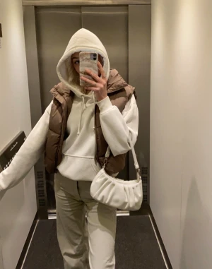 Brun dunväst från Bik Bok - Säljer en brun dunväst från Bik Bok i storlek XS (passar även S). Västen har en hög krage, quiltad design och dragkedja framtill. Går att justera vid midjan! Tillverkad i syntetmaterial med återvunnet foder. Perfekt att styla över hoodies eller tröjor🤎