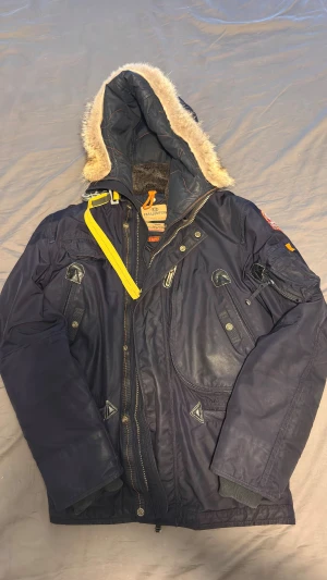  Parajumpers parkajacka + mössa - Säljer min Parajumpers vinterjacka tillsammans med en Parajumpers vintermössa – perfekt som ett stilrent vinterkit från samma exklusiva märke. Jackan är använd i ca 1 år, men bara under vissa vinterperioder, och är fortfarande i bra skick och väldigt varm.  ✔ Äkta ✔ Varm och bekväm ✔ Första modellen  Den extra dragkedjan saknas, men jackan fungerar utmärkt ändå. Har man en egen dragkedja går det enkelt att fixa.  