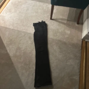 Svarta bootcut jeans från Zara - Svarta jeans från Zara med bootcut passform och råa, slitna kanter vid bensluten. Klassisk femficksmodell med knapp och dragkedja framtill. Jeansen har en snygg, mörk ton och är tillverkade i ett stretchigt bomullsmaterial för skön passform.