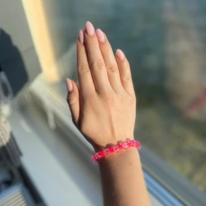 Handgjort rosa armband - Snyggt armband med starkt rosa och transparenta pärlor i plast. Armbandet ger en stilren och cool finish look. Pärlorna är runda och sitter på en elastisk tråd som gör det enkelt att ta på och av. Perfekt för dig som gillar färgglada accessoarer och vill sticka ut lite extra.