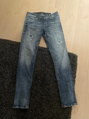 Jack and jones jeans blå - Säljer ett par sköna jeans från jack and jones i blå tvätt med slitna detaljer och slim passform.