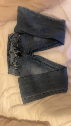 True Religion blå jeans bootcut - Säljer ett par klassiska blå jeans från True Religion med bootcut och ikonisk broderad ficka bak. Passar mig som är runt 163 cm. Köpta för 1400