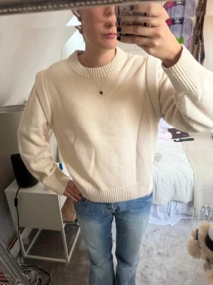 Beige stickad tröja från & Other Stories - Säljer en beige stickad tröja från & Other Stories. Tröjan har rund hals, breda ribbade muddar vid ärmslut och nederkant samt en loose passform. Tröjan har snygga detaljer vid axlarna vilket gör den till något extra!