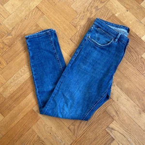 Blå tapered jeans från Massimo Dutti - Snygga blå jeans från Massimo Dutti i klassisk femficksmodell. Jeansen har tapered fit, vilket ger en smalare passform nedtill. Tillverkade i mjukt denimtyg med diskreta slitningar och detaljerade sömmar. Perfekta för en avslappnad och stilren look.