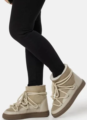 Beige Inuikiis boots med snörning - Säljer ett par beige boots från inuikiis med grova snören och platt brun sula. Skorna har en rund tå och är tillverkade i mocka och skinn, med en mysig fodrad insida. Perfekta för vintern och har en cool, chunky look som sticker ut.