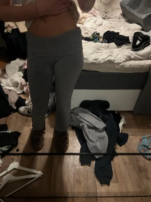 Grå ribbade mjukisbyxor - Mysiga grå mjukisbyxor med bred ribbad midja som ska vikas ned och raka ben. Byxorna är stickade i ett mjukt material som känns skönt mot huden och har en enkel, clean look. Perfekta för chill dagar hemma eller när du vill vara extra bekväm.