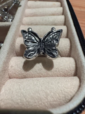 Silvrig ring med fjäril - Cool ring i silverfärgad metall med en stor fjäril som detalj. Fjärilen har snygga mönster på vingarna och en 3D-effekt som gör att den verkligen sticker ut. Perfekt för dig som vill ha något unikt och iögonfallande på fingret.