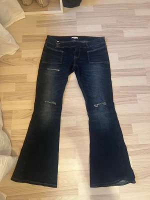 Mörkblå bootcut jeans med slitningar - Lågmidjade bootcut jeans från Gina tricot. Säljer då dom inte kommer till användning.💞💞💞
