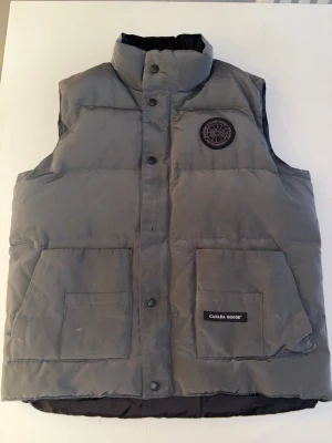 Grå Goose väst - Hej, säljer nu min CG väst riktigt fett med black label. (Storlek M) riktigt varm och bekväm. Om du vill fräsha upp din garderob med lite nya kläder så borde du köpa hem något från oss.