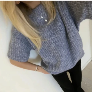 Blå stickad tröja från H&M - Mysig och skön blå stickad (lite oversized) tröja från H&M i storlek 36. Tröjan har korta ärmar, rak passform och ribbad struktur. 