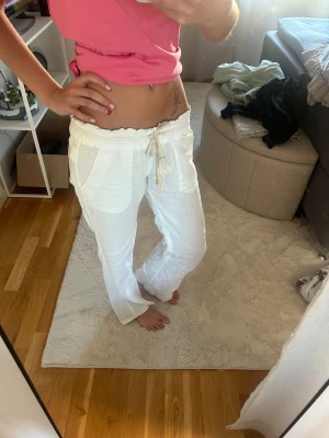 Vita linnebyxor med snörning - Säljer ett par vita linnebyxor med avslappnad passform och snörning i midjan. Byxorna har fickor fram och bak, elastisk midja och raka ben. Perfekta för varma dagar och chill stil. Jätte populära från Roxy 