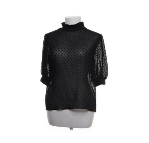 Svart prickig blus från Zara - Säljer en svart transparent blus från Zara med prickigt mönster. Blusen har halvpolo, puffiga trekvartsärmar och ribbade muddar vid hals och ärmslut. Perfekt för dig som gillar coola detaljer och vill sticka ut lite extra.