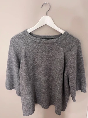 Grå stickad tröja från 157 XS - Mysig grå stickad tröja från lager 157 i storlek XS. Tröjan har en rundad halsringning och långärmade ärmar med ribbade muddar. Perfekt för kyliga dagar och enkel att matcha med jeans eller kjol. Materialet är mjukt och ger en skön känsla.