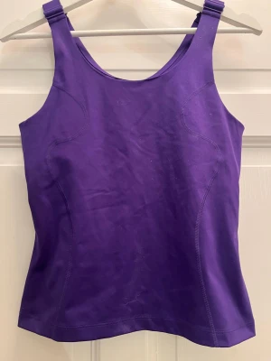Lila linnetopp från H&M Move inbyggd bh - Säljer en lila linnetopp från H&M Move i storlek M. Toppen har breda axelband och är figursydd med sportig känsla. Perfekt för träning eller när du vill ha en bekväm och snygg look. Materialet är stretchigt och följsamt.
