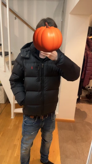 Svart pufferjacka från Polo Ralph Lauren - Svart pufferjacka från Polo Ralph Lauren med röd broderad logga på bröstet. Jackan har huva, flera dragkedjefickor och grov dragkedja framtill. Materialet är syntet och jackan är quiltad för extra värme. Perfekt för kalla dagar och har en clean, sportig look. Köpt på SNS för ca 1-2 år sen, inga hål/skador, äkta såklart. 