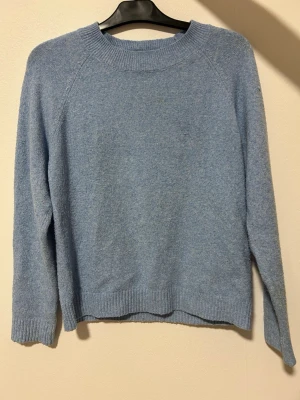 Ljusblå stickad tröja Vero Moda - Mysig ljusblå stickad tröja från Vero Moda i storlek M. Tröjan har rund halsringning, ribbade muddar vid ärmslut och nederkant samt lång ärm. Perfekt för kyligare dagar och enkel att matcha med jeans eller kjol.