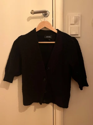 Svart kofta från Monki - Mysig svart kofta från Monki i storlek XS. Koftan har v-ringad hals, trekvartsärmar och knäpps med knappar framtill